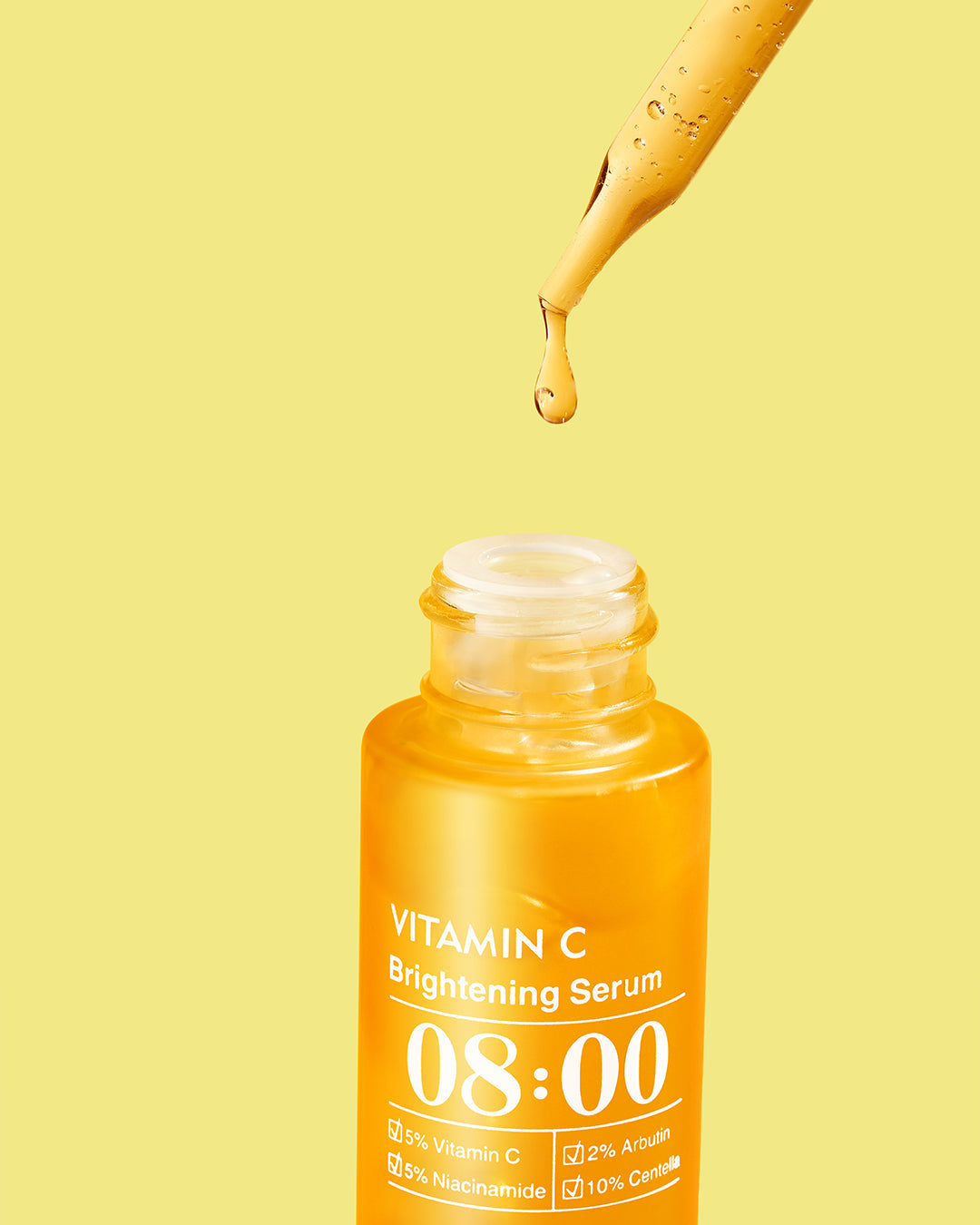 Vitamin C brightening serum bottle with dropper on a yellow background