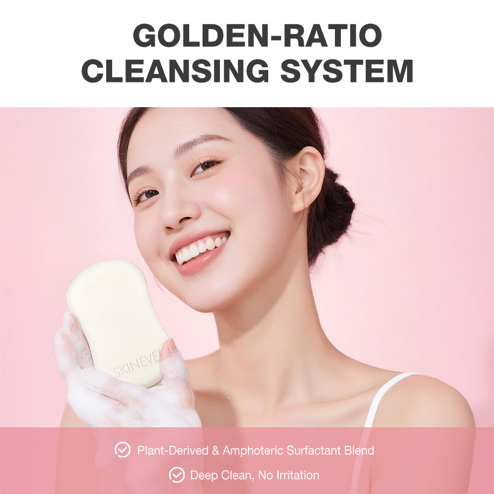 A smiling woman in a white tank top holds a cream-colored cleansing bar wrapped in a white glove against a soft pink background. Large text at the top reads 'GOLDEN-RATIO CLEANSING SYSTEM,' and smaller text at the bottom highlights plant-derived surfactant blend and deep clean, no irritation.