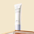 A white tube of SKINEVER Water Light Serum Sunscreen SPF 50 PA++++ stands upright on a reflective surface against a solid beige background.