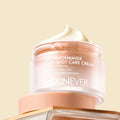 SKINEVER 10% Niacinamide Dark Spot Care Cream in a frosted glass jar with a peach-colored lid, topped with a swirl of white cream, set against a solid pale beige background.